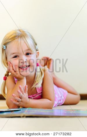 cute blondynka z warkoczykami śmieje się i czyta książki w przedszkolu