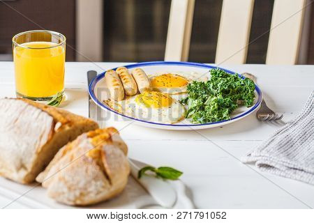 Breakfast Served With Fried Eggs, Salad, Muffins And Orange Juice On White Wooden Table In The Kitch
