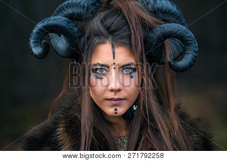 Outdoor Portrait Of Beautiful Scandinavian Viking Woman Warrior With Blue Eyes Wearing Ram Horns Loo