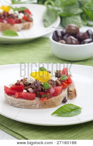 Nahaufnahme der köstliche Oliven Tapenade Tomaten Bruschetta mit Feta-Käse und frischem Basilikumblätter.