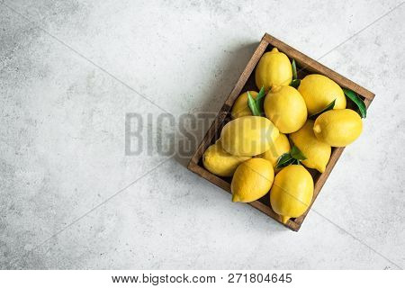 Lemons With Green Leaves In Box On White Stone Background, Top View, Copy Space. Organic Fresh Citru