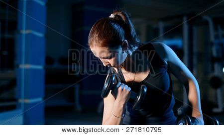A Girl Performs A Concentrated Bench Press Sitting With The Help Of Dumbbells.