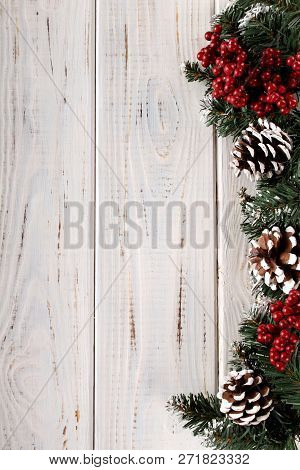 Spruce Branches, Cones And Red Berries On A White Wooden Background. Background For Christmas And Ne
