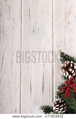 Spruce Branches, Cones And Red Berries On A White Wooden Background. Background For Christmas And Ne
