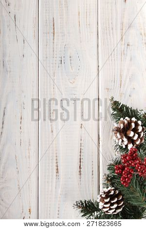 Spruce Branches, Cones And Red Berries On A White Wooden Background. Background For Christmas And Ne