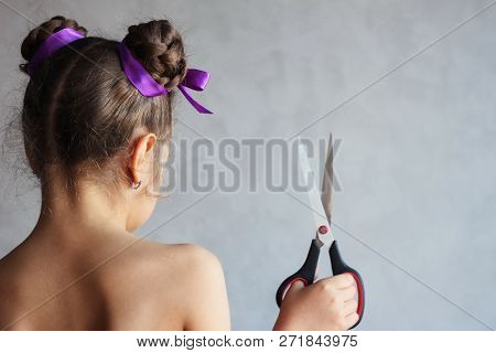 Hairstyle and haircare concept. Hairdressing services. Girl holding scissors. Hair with ribbons.