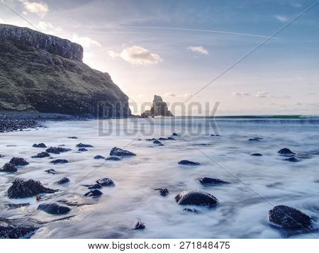 Sea Stack Sharp Silhouette By Sunset Sky. Evening Light On The Rocks, Boulders And Cliff Face Of Tal