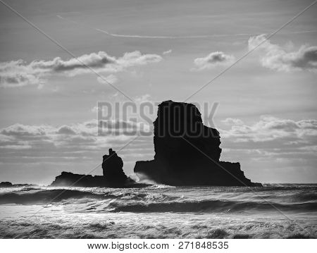 Cloudy Evening On Rocky Shore At Sunset. Sunset Mirroring In  Sea Water And Large Cracked Rocks With