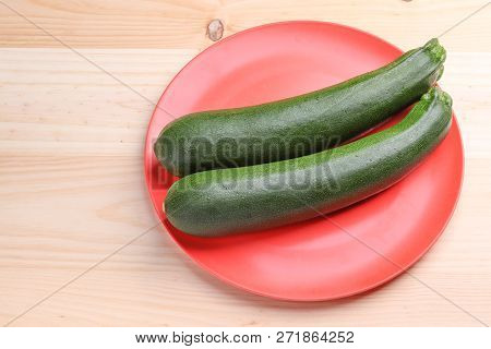 Fresh Zucchini On A Red Plate And Wooden Background. Healthy And Healthy Food.