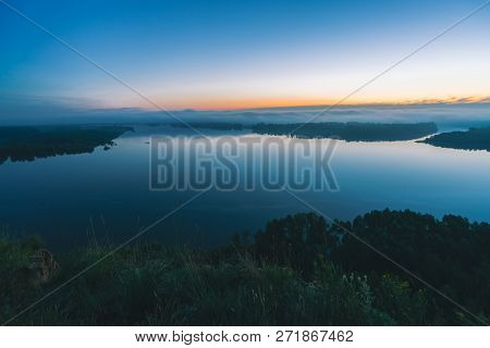Mystical View From High Shore On River. Riverbank With Forest Under Mist. Early Haze Above Trees. Or