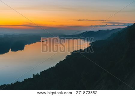 View From High Shore On River. Riverbank With Forest Under Thick Fog. Gold Dawn Reflected In Water. 