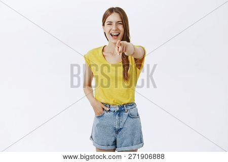 Portrait Of Amused Cruel Stylish Popular Girl In Yellow T-shirt Pulling Index Finger At Camera And L