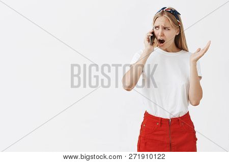 Studio Shot Of Displeased Moody Girlfriend With Blond Hair Frowning And Compaining While Talking On 