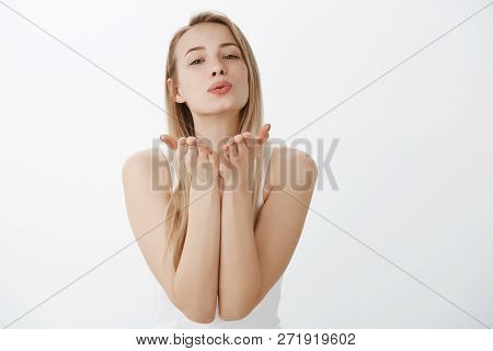 Tender And Flirty Young Attractive Female With Blond Hair In Tank-top Raising Hands Near Folded Lips