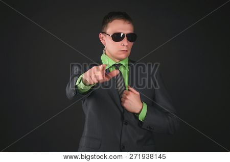 Serious Security Agent In Sunglasses And Suit Is Showing Forward By His Index Finger Isolated On Bla