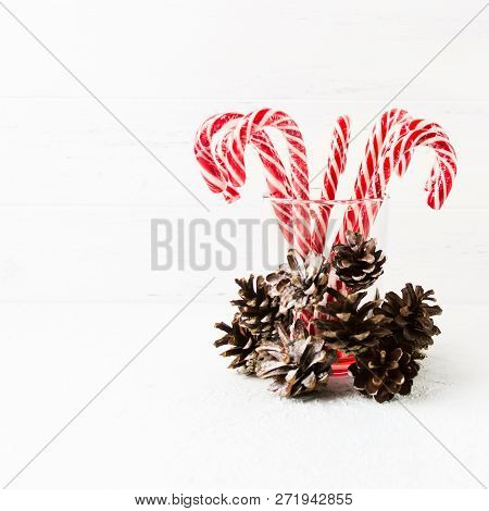 Many Red Christmas Candy Canes In Glass With Pine Cones Decoration