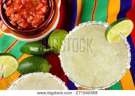 Cinco de Mayo Concept: Margaritas and Salsa on a colorful  table cloth, with limes, and peppers.