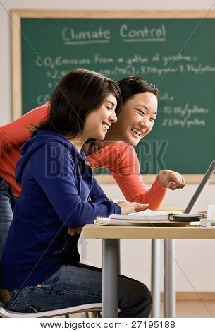 Bestemt studerende med laptop laver lektier med ven i skole klasseværelse