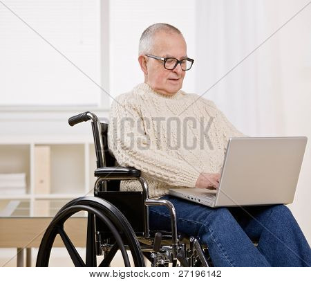 Uomo disabile in sedia a rotelle digitando sul computer portatile