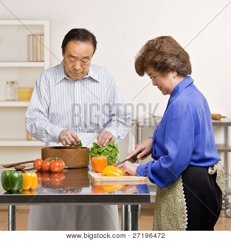 คนดีที่เตรียมสลัดบริสุทธ์กับภรรยาในครัวสำหรับมื้อเย็น