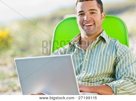 Man använder laptop på stranden