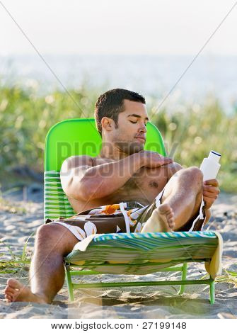 Homme, application de lotion écran solaire à la plage