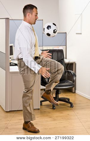 Homme d'affaires jouant avec ballon de foot au bureau