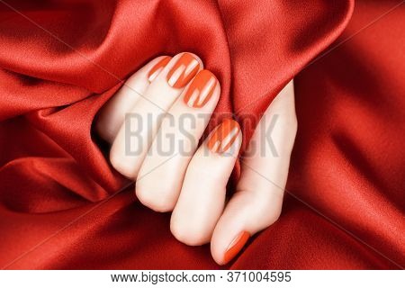 Female Fingers With Bright Red Manicure On A Red