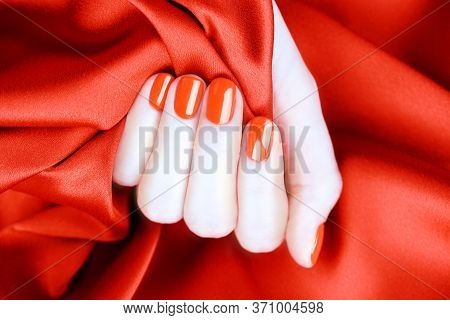 Female Fingers With Bright Red Manicure On A Red
