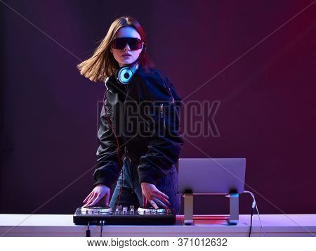 Stylish Dj Girl With Headphones And Glasses On The Bomber Jacket Mixes The Music At The Party And Ne