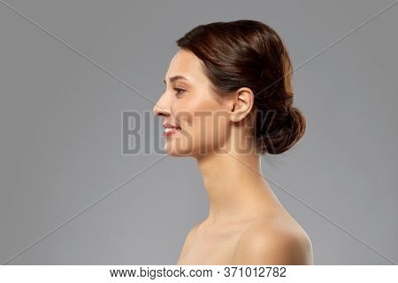 beauty, bodycare and people concept - profile of beautiful young woman with bare shoulders over grey background