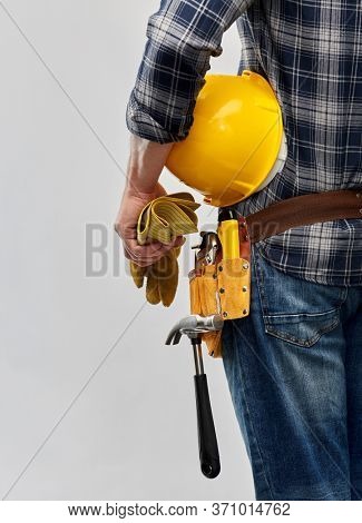 repair, construction and building - male worker or builder with helmet and working tools on belt over grey background