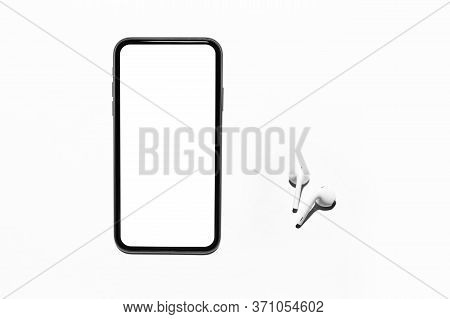 Top View Of Modern Smartphone With Empty Mockup Up On Screen Beside Wireless Earphones Or Earbuds. I