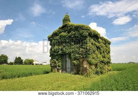 An Old Ivy-covered Church In Countryside In A Summer Day Against A Blue Sky With Some Clouds - Conce