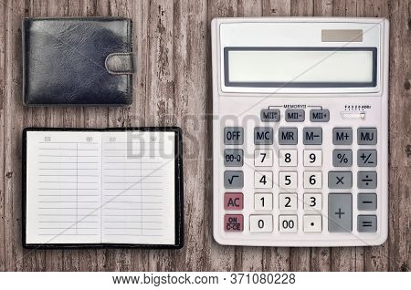 Office Flat Lay Composition With Calculator, Address Book And Black Purse On Brown Wooden Table Back