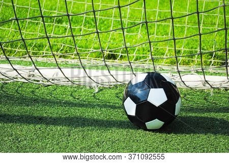 Closeup Of A Soccer Ball In The Goal Net On A Green Lawn. Sports Group Games On A Professional And A