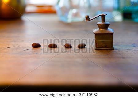 โรงสีขนาดเล็กทองเหลืองกาแฟและเมล็ดกาแฟบนโต๊ะเก่า