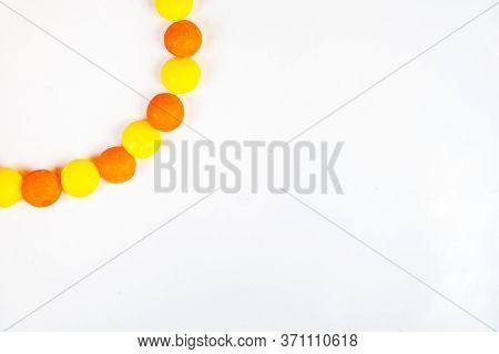 White Background With Round Candys In The Left Corner. Border Of Sweet Yellow And Orange Candys