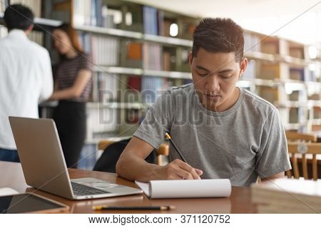 Asian Young Student Studying And Reading Book In Library