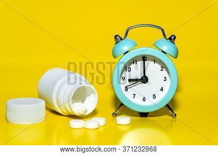 Alarm Clock, Pills, A Jar Of Medicine On Yellow Background. Awakening Up Early In The Morning By Cal