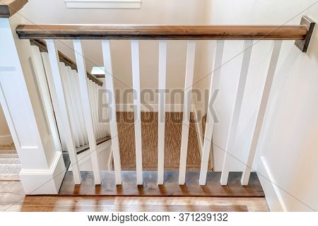 U Shaped Stairway Of Home With Brwon Handrail Supported By White Balusters