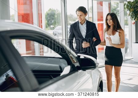 Stylish And Elegant Couple In A Car Salon
