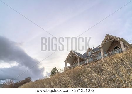 Home At Neighborhood Sitting On Top Of Hill Gainst Snowy Mountain And Cloudy Sky