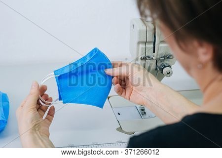 Stepwise Stitching Of Blue Fabric Medical Masks. Close-up Hands Holding A Ready-made Mask. The Conce