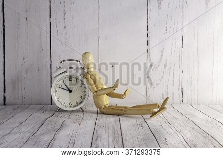 White Vintage Alarm Clock And Wooden Mannequin Supported On Wood Table And Wood Background