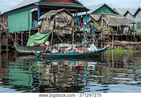 Kampong Phluk, Cambodia - December 4, 2011:  A Woman Paddling A Heavily Laden Wooden Boat Through Th