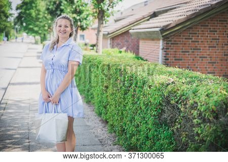 Attractive blonde in a short dress on a cozy green street in Skals Denmark
