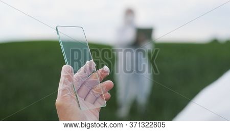 View Over Shoulder Of Farmer Ecologist In Protective Suit Tapping On Glass Transparent Screen. Close