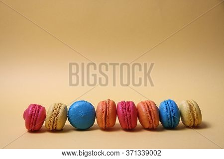 Macaroons Of Differrent Colours In A Line Isolated On Yellow Background. Image Contains Copy Space