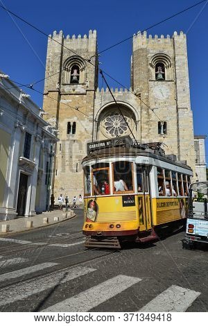 Lisbon, Portugal - July 2, 2019:  A Famous Yellow Tram 28 Passing In Front Of Santa Maria Cathedral 